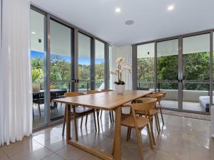 a dining room with a table and chairs and windows at Cotton Beach 94 Mid-Floor Penthouse with Bush View in Casuarina