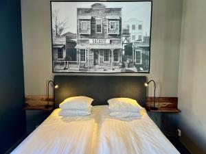 een bed met twee kussens en een foto van een huis bij Hotell Siesta in Karlskrona