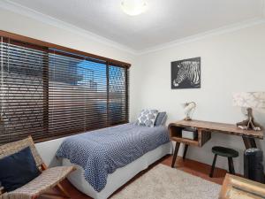 a bedroom with a bed and a desk and a window at Deja Blue on the Creek in Kingscliff