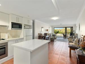 a kitchen with white appliances and a living room at Deja Blue on the Creek in Kingscliff