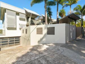 a white house with palm trees in front of it at Deja Blue on the Creek in Kingscliff