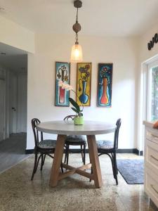 uma sala de jantar com uma mesa com cadeiras e pinturas em Cozy Chalet near the Design District em Miami