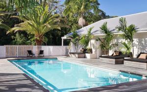 a swimming pool with two chairs next to a house at Atlantic Byron Bay in Byron Bay