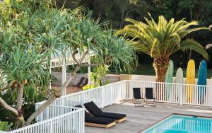 a resort with a pool and palm trees and surfboards at Atlantic Byron Bay in Byron Bay