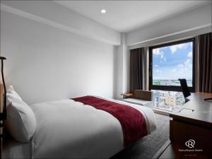 山形市にあるダイワロイネットホテル山形駅前のベッドと大きな窓が備わるホテルルームです。