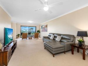 a living room with a couch and a flat screen tv at Tradewinds 1 on Kingscliff Beach in Kingscliff