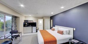 a bedroom with a large bed and a dining room at Capri on Fenton in Rotorua