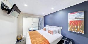 a bedroom with a large bed with an orange blanket at Capri on Fenton in Rotorua