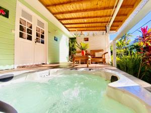 bañera de hidromasaje en el patio de una casa en Villa Gaïa - Bungalow Ti-Zen et son jacuzzi niché dans un jardin tropical, séjour en amoureux en Le Diamant