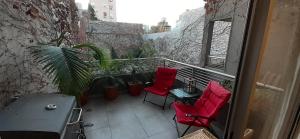 balkon z 2 czerwonymi krzesłami i stołem w obiekcie CONFORT BELGRANO w BuenosAires