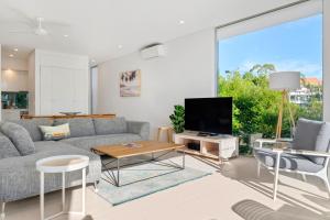 a living room with a couch and a tv at The Rise Noosa in Noosa Heads