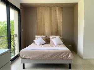 una camera da letto con un letto con cuscini bianchi e una finestra di Villa californienne à 10 minutes à pied du centre-ville a Vence