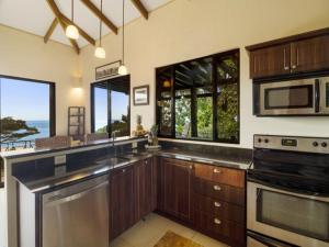 cocina con electrodomésticos de acero inoxidable y ventanas grandes en Villas by Tekoa, en Uvita