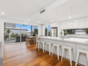 a kitchen with white counters and white counter stools at Sunrise Mansion with Pool in Kingscliff