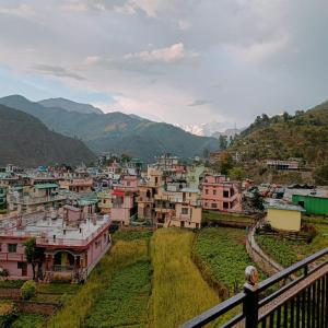 a woman standing on a balcony overlooking a city at An Himalayan View by StayApart in Barkot