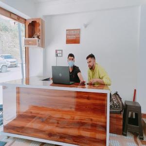 two men sitting at a counter with a laptop at An Himalayan View by StayApart in Barkot