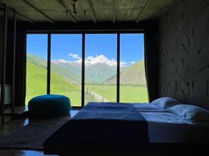 a bedroom with a bed and a large window with mountains at Gzaze in Stepantsminda