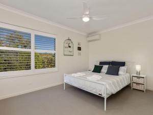 a white bedroom with a bed and a window at Salty Pause at Bondi House - Pet Friendly! in Kingscliff