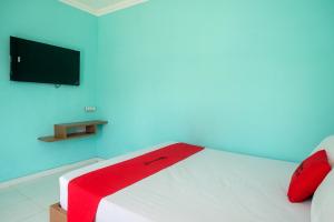 a bedroom with a white bed with a red blanket on it at RedDoorz @ Jakal Atas KM 7 in Kejayan