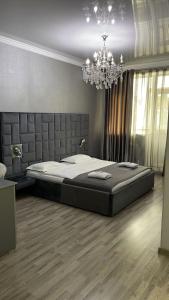 a bedroom with a large bed and a chandelier at Апартаменты в центре города ЖК Арман in Aktobe