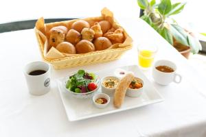 a table with a plate of food and a basket of bread at HOTEL Third Place Hakata in Fukuoka