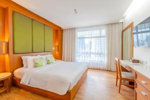 a bedroom with a large bed with a desk and a window at Pinnacle Lumpinee Park Hotel SHA Plus in Bangkok