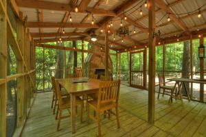 eine abgeschirmte Veranda mit einem Holztisch und Stühlen in der Unterkunft Sweet Serenity Creek in Cherry Log