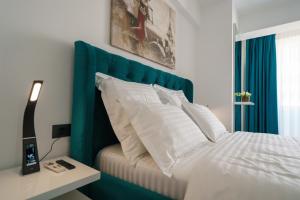 a bed with a blue head board and white pillows at The Queen Infinity Beach Pool&Spa Mamaia Nord in Mamaia Nord