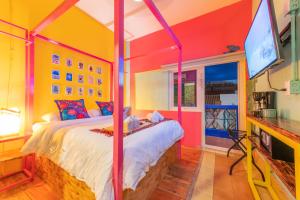 Dormitorio colorido con cama y TV en Casa Colibrí Malecón, en Puerto Vallarta