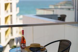 una botella de vino sentada en una mesa con copas en The Queen Infinity Beach Pool&Spa Mamaia Nord en Mamaia Nord – Năvodari