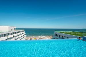 a large swimming pool with a view of the ocean at The Queen Infinity Beach Pool&Spa Mamaia Nord in Mamaia Nord