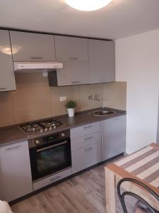 a kitchen with white cabinets and a stove top oven at APARTMAN Viktor in Maslenica