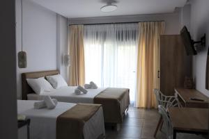 um quarto de hotel com duas camas e uma janela em Nautico Rooms em Keramoti