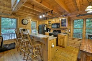 a log cabin kitchen with a large center island with bar stools at Lakeview Escape in Ellijay +26 photos