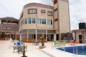 un edificio con piscina, mesas y sillas en Alafia Hotel Ketou, en Kétou