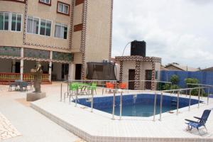 a building with a swimming pool with a tv in it at Alafia Hotel Ketou in Kétou