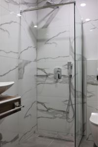 a glass shower door in a bathroom with a toilet at Nautico Rooms in Keramoti