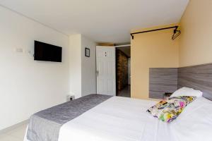 1 dormitorio con 1 cama blanca y TV de pantalla plana en EDIFICIO Niza80 ibague, en Ibagué