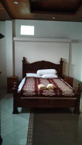 a bedroom with a wooden bed with two shoes on it at Uma Pejeng in Ubud