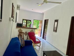 uma sala de estar com um sofá azul e uma cadeira vermelha em Lovely Garden Villas em Pantai Cenang