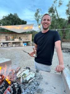 Ein Mann steht neben einem Grill in der Unterkunft Le Biadelle - Country Boutique Apartments - Villa Laura Ostuni in Ostuni