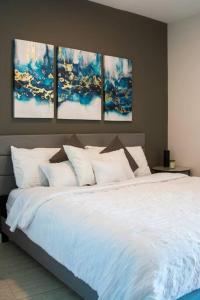 ein Schlafzimmer mit einem weißen Bett mit vier Gemälden an der Wand in der Unterkunft Luxury Oceanview Studio at Miami Design District in Miami