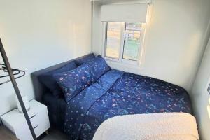 a small bedroom with a blue bed and a window at Honey Wines Aust. Tiny House in Broke