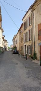 eine leere Straße mit einem Auto neben den Gebäuden in der Unterkunft La Maison de la Cloche in Puimoisson