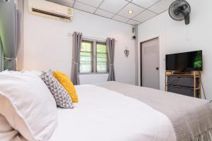 um quarto com uma cama branca e uma televisão de ecrã plano em Garden Home 1 em Haad Yao