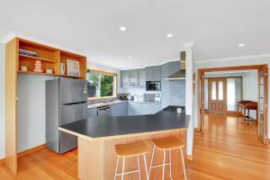 a kitchen with a black counter and two stools at The BEST Scamander Beach House! in Scamander