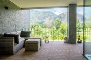 a living room with a couch and a balcony with mountains at [Free parking-Golf-Garden] in Losone