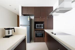 M Estate 2BR Private Residence, 300m to BTS Chit Lom في بانكوك: مطبخ مع قمم منضدة بيضاء ودواليب بنية