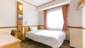 um quarto com uma cama branca e uma janela em Toyoko Inn Shin-Osaka Chuo-guchi Shinkan em Osaka