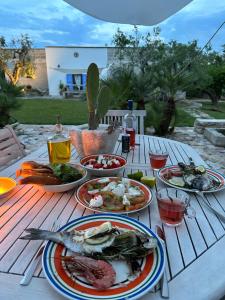 een houten tafel met borden eten erop bij La Monacedda - Country Boutique Apartments - Villa Laura Ostuni in Ostuni